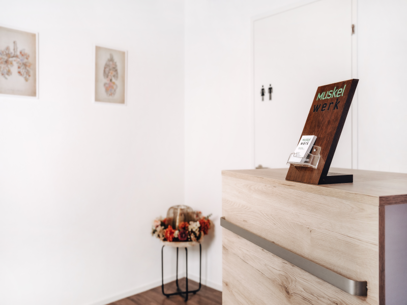 Empfangsbereich mit Holztheke und Aufsteller mit Logo der Muskelwerk GmbH