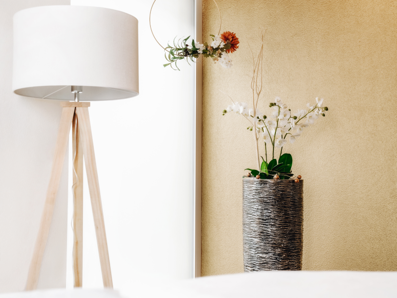 Stehlampe und dekorative Vase mit weissen Orchideen in einem hellen, modernen Raum
