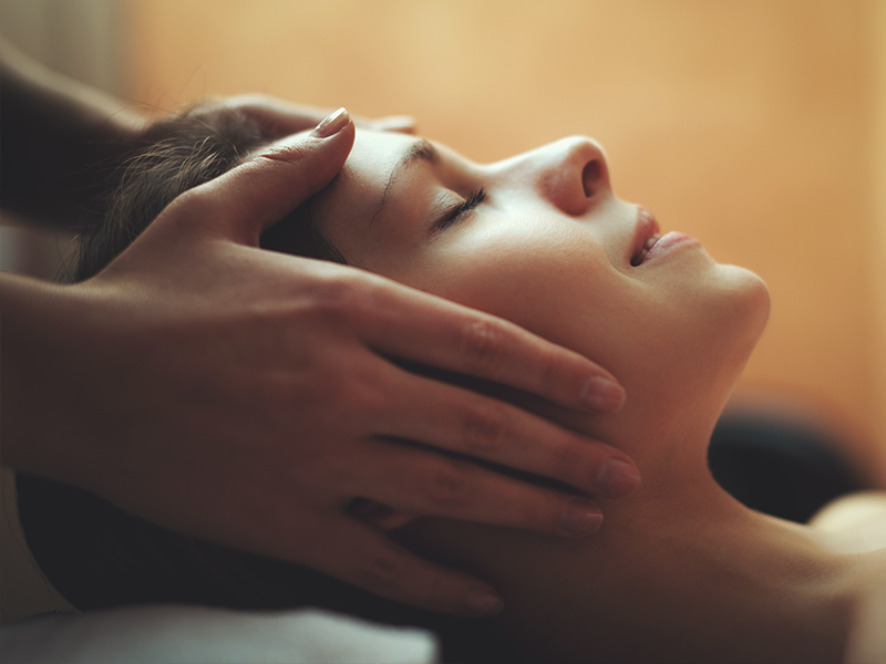 Frau bei entspannender Gesichtsmassage mit geschlossenen Augen
